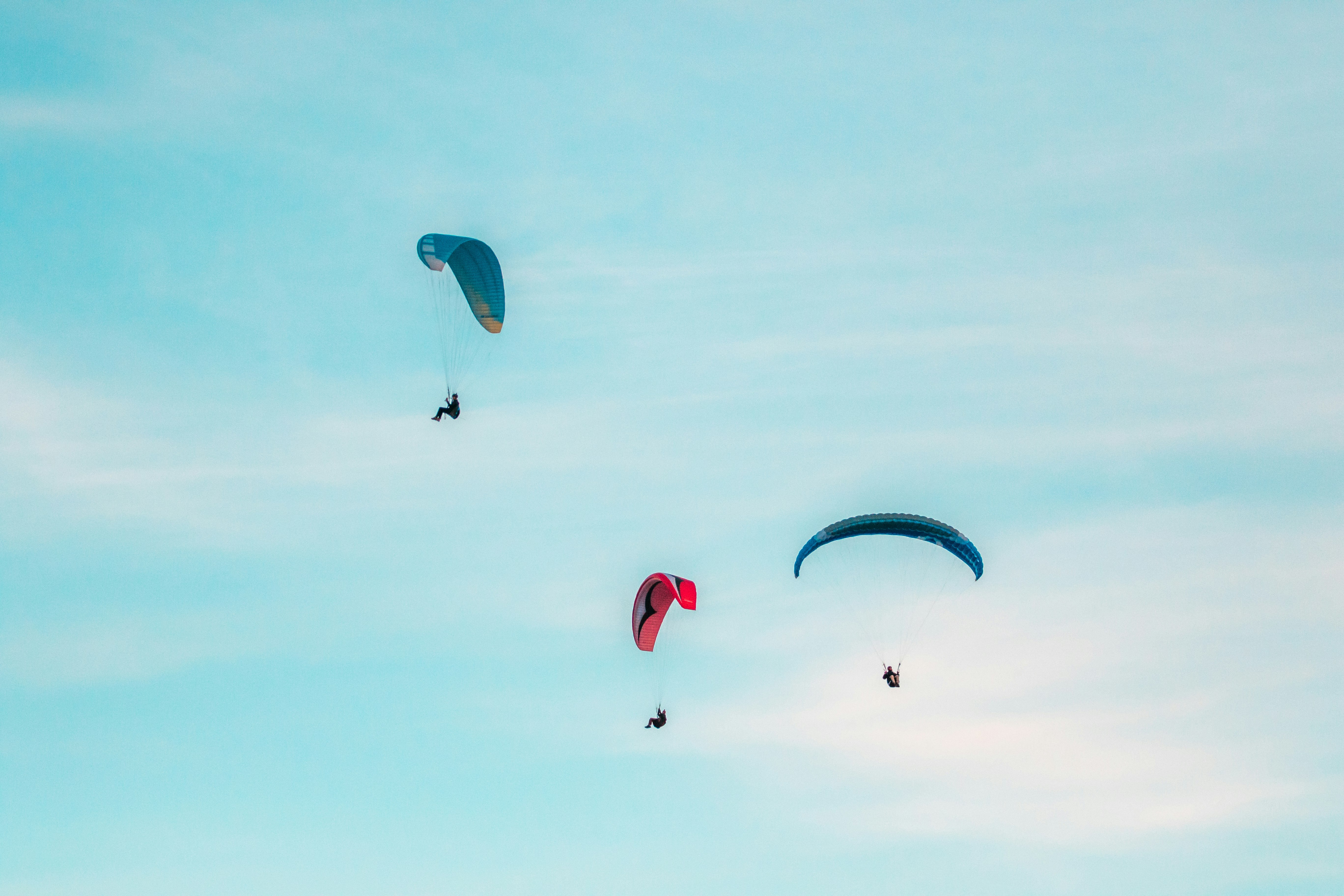 three person midair with parachutes